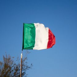 Low angle view of flag against blue sky