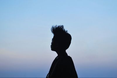 Silhouette woman with spiky hair against clear sky