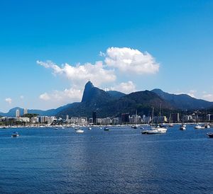 Sailboats in sea with city in background