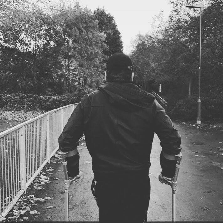 REAR VIEW OF A MAN WITH UMBRELLA ON THE ROAD