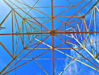Low angle view of electricity pylon against blue sky