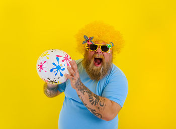 Midsection of man holding umbrella against yellow background