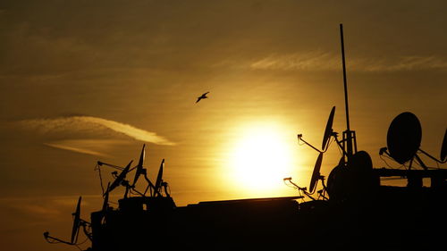 Silhouette of birds flying over sea against orange sky