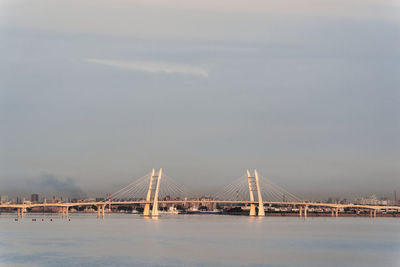 Suspension bridge over river against sky at sunset