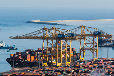 Cranes at harbor against sky