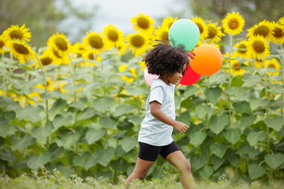 Full length of boy on yellow flowers in field