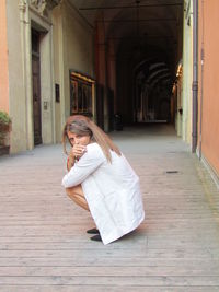 Side view of woman holding cigarette crouching on road