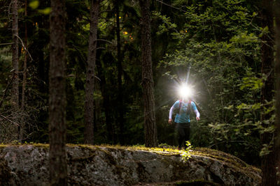Man walking through forest with headlight