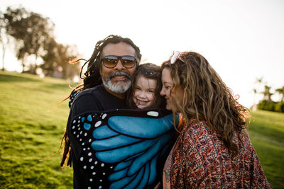 Aunt, uncle and niece hugging and posing at sunset