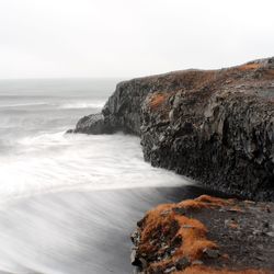 Rock formation on beach against sky