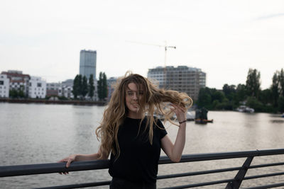 Portrait of beautiful woman by railing against river