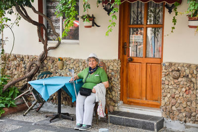 Portrait of smiling woman sitting on chair outside house