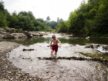 Shirtless boy walking in river