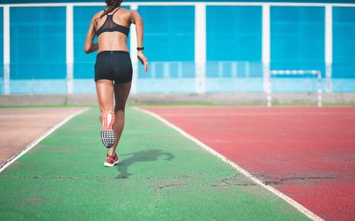 Rear view of woman running on sports track