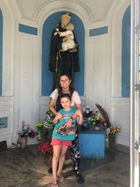 Portrait of smiling girl standing against door