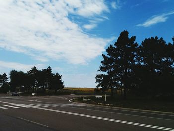 Road by trees against sky