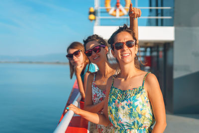 Portrait of smiling young woman holding sunglasses