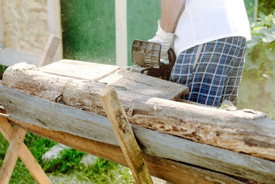 Chainsaw in the hands of a worker cutting firewood, close-up