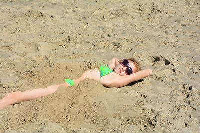 High angle view of teenager girl lying on sand at beach