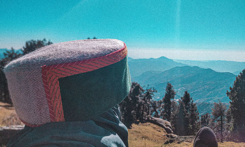 Rear view of person looking at mountains against sky