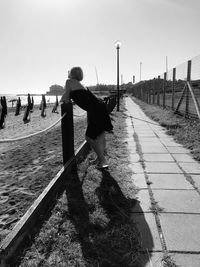 Woman walking on footpath against sky