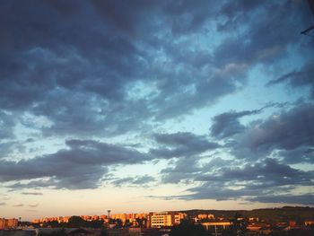 Buildings in city against dramatic sky