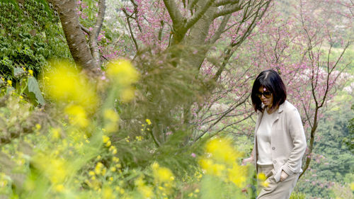 Side view of young woman standing against trees