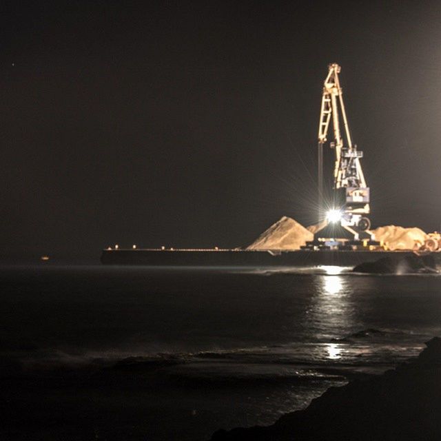 night, illuminated, water, copy space, sea, clear sky, built structure, sky, architecture, ferris wheel, transportation, waterfront, outdoors, nautical vessel, amusement park, crane - construction machinery, no people, amusement park ride, nature, low angle view