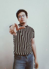 Portrait of young man standing against wall