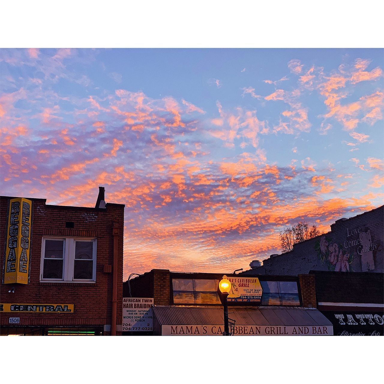 LOW ANGLE VIEW OF ILLUMINATED BUILDINGS AGAINST SKY DURING SUNSET