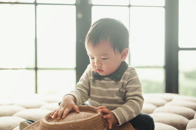 Cute boy holding hat sitting at home