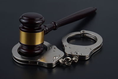 Close-up of handcuffs with gavel on black table