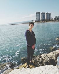 Full length of young man standing on rock against sea