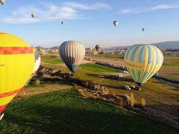 Hot air balloons flying over land against sky