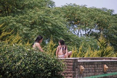 Young couple sitting on riverbank against sky