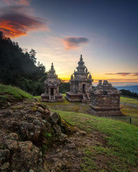 Temple by building against sky during sunset