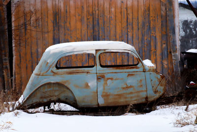 Abandoned car on snow covered land