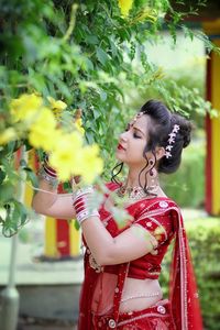 Beautiful young indian woman standing against flowers