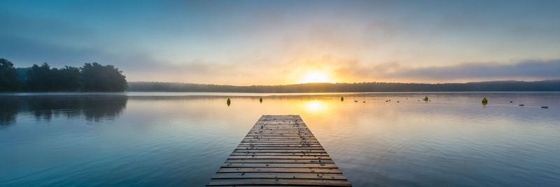 Pier over lake against sky during sunset