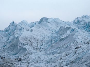 Scenic view of glacier with people walking