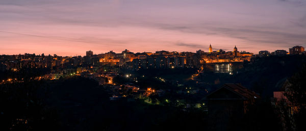 Illuminated cityscape against sky at dusk