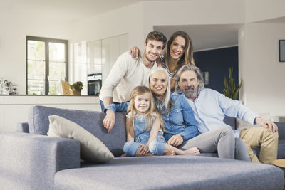 Extended family sitting on couch, smiling happily