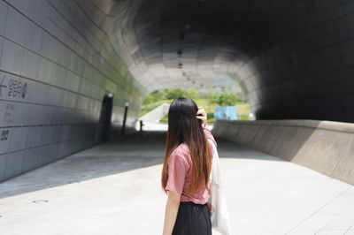 Rear view of woman standing against wall