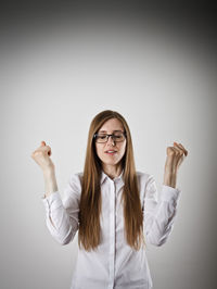 Portrait of young woman standing against white background