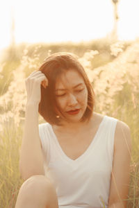 Woman looking away while sitting by plants 