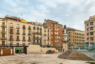 Buildings in city against cloudy sky