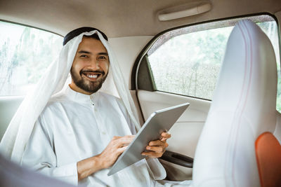 Midsection of man using mobile phone while sitting in car