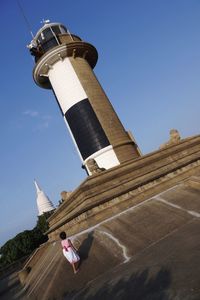 Tilt shot of girl at lighthouse against sky