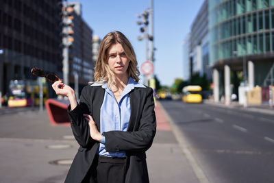 Portrait of young woman using mobile phone while standing in city