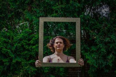 Digital composite of woman holding frame against trees